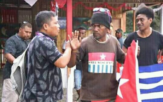 Ben Didiomea mengangkat bendera West Papua, sementara staf delegasi Indonesia mencoba menjauhkannya dari stan mereka. - RNZI/ Facebook/ Ben Didiomea